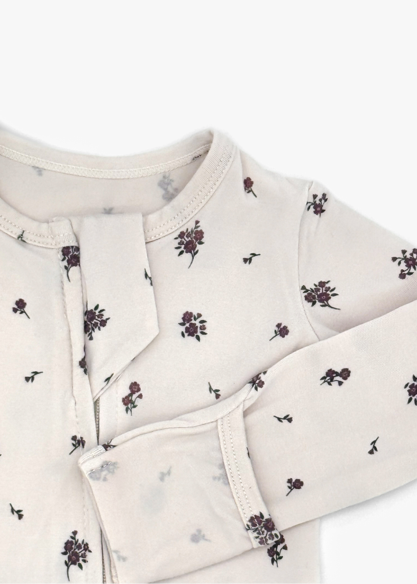 Milana Label Zippered Sleeper in the colour Birch Floral on an off white background. Highlighting the fold-over mitts.
