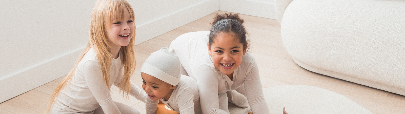 Three kids playing together on the floor in their matching Milana Label outfits.
