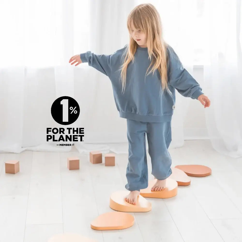 A child wearing a blue sweatshirt and pants set playing on wooden blocks.