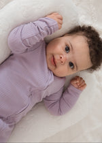 Angled close-up shot of a baby looking directly at the camera while wearing the Lavender Blush ribbed baby sleeper PJ.