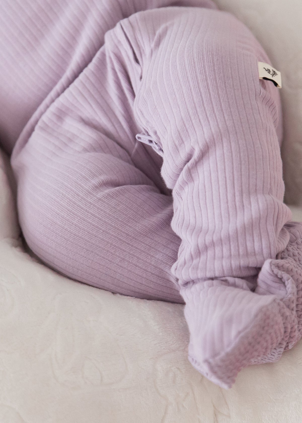 Close-up detail of a baby wearing the Lavender Blush organic cotton footie sleeper, highlighting the soft ribbed fabric and enclosed footies.