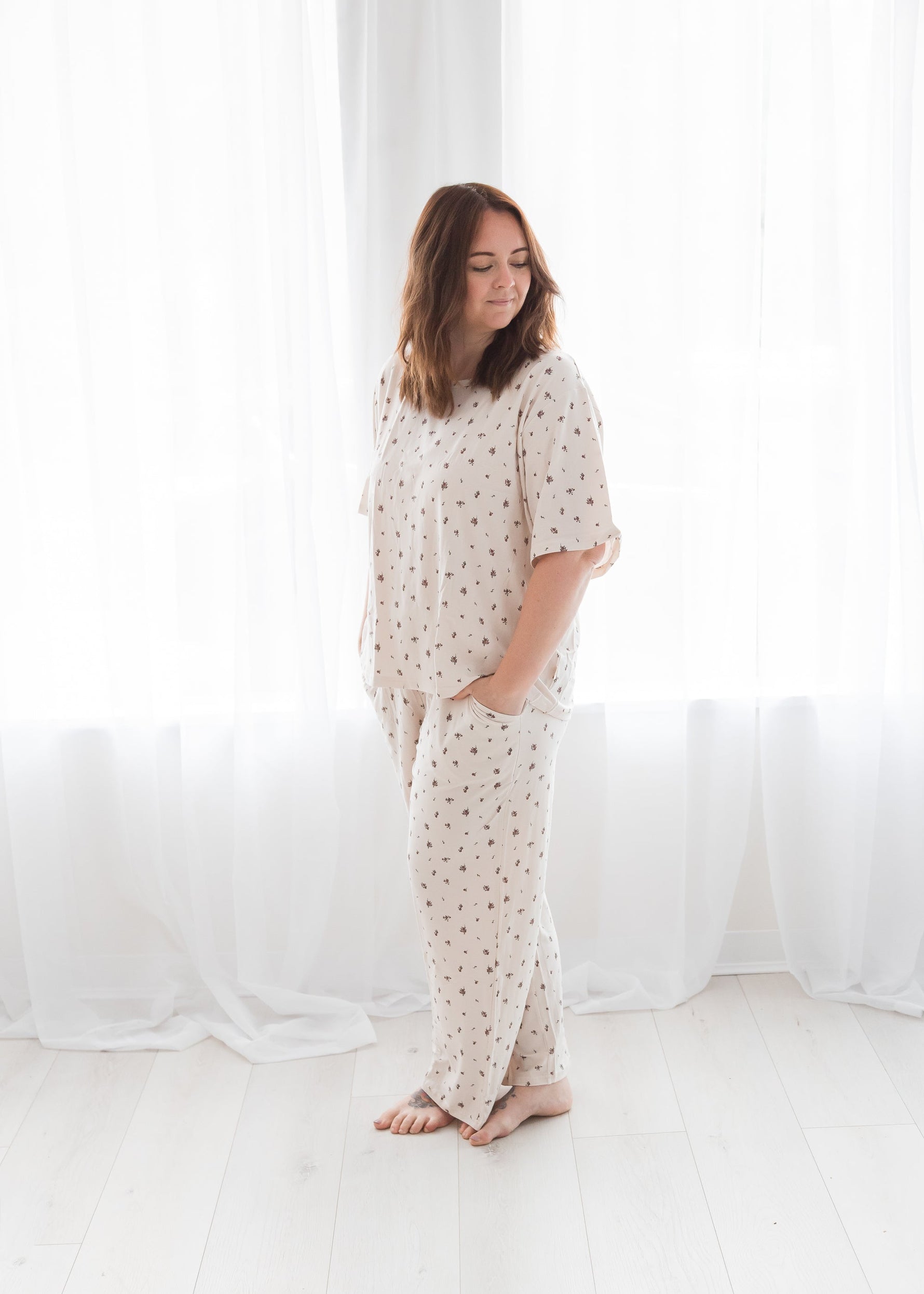 Woman standing in a bright room modeling a short-sleeve Tencel pajama set with a delicate birch floral print.