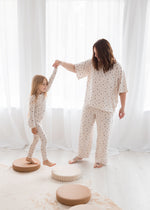 Mother and daughter holding hands and playing in matching mommy-and-me Tencel pajama sets in a birch floral print.