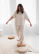 Woman walking on stepping stones, wearing a short-sleeve Tencel pajama set in an off-white floral print.
