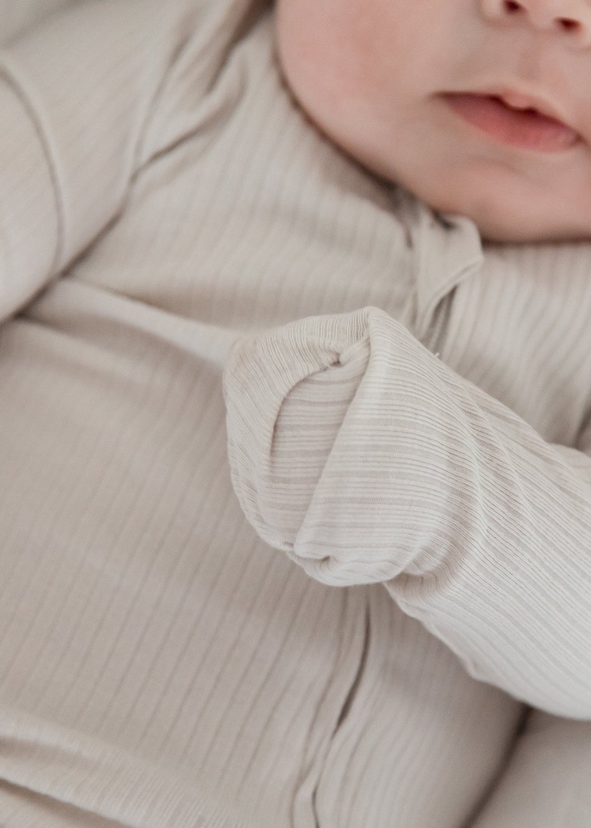 Close-up detail of the fold-over scratch mitts feature on the sleeve of the Milana Label Stone greige ribbed baby sleeper.