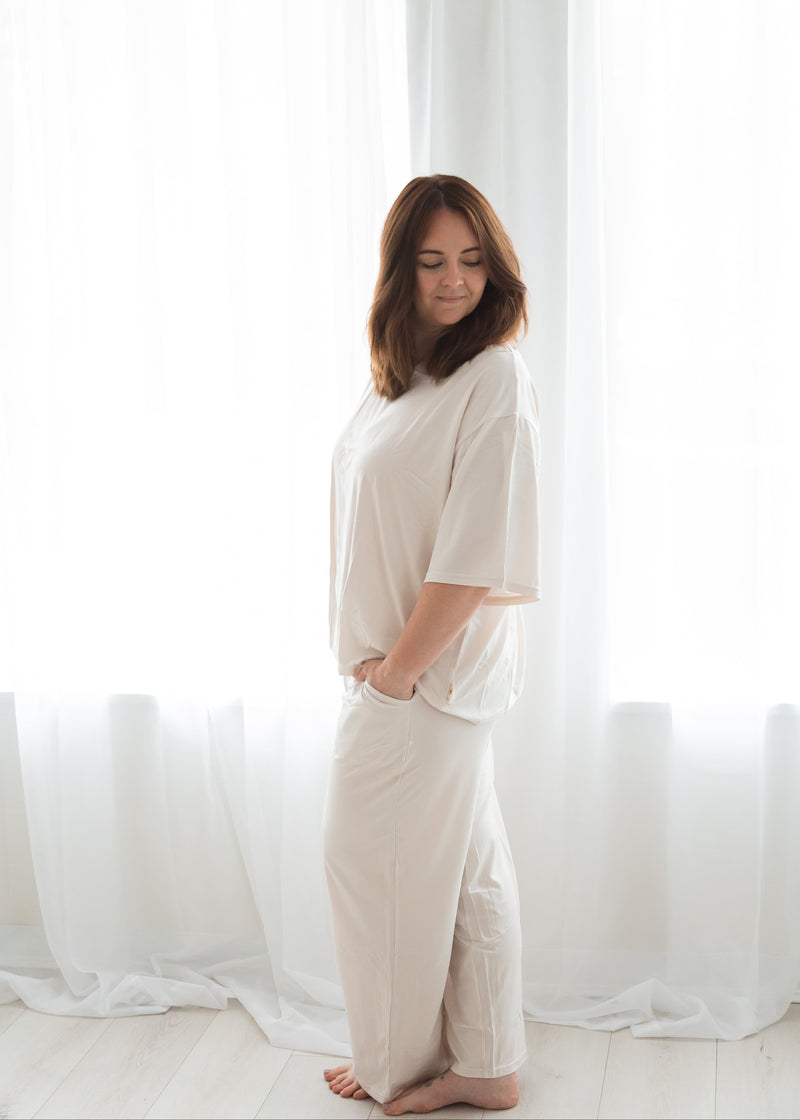 A woman wearing Milana Label PJ's in a neutral colour, right side angle.