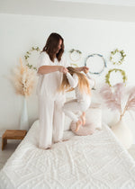 A mom and her daughter playing in the bedroom while wearing matching PJ's in the colour Birch.