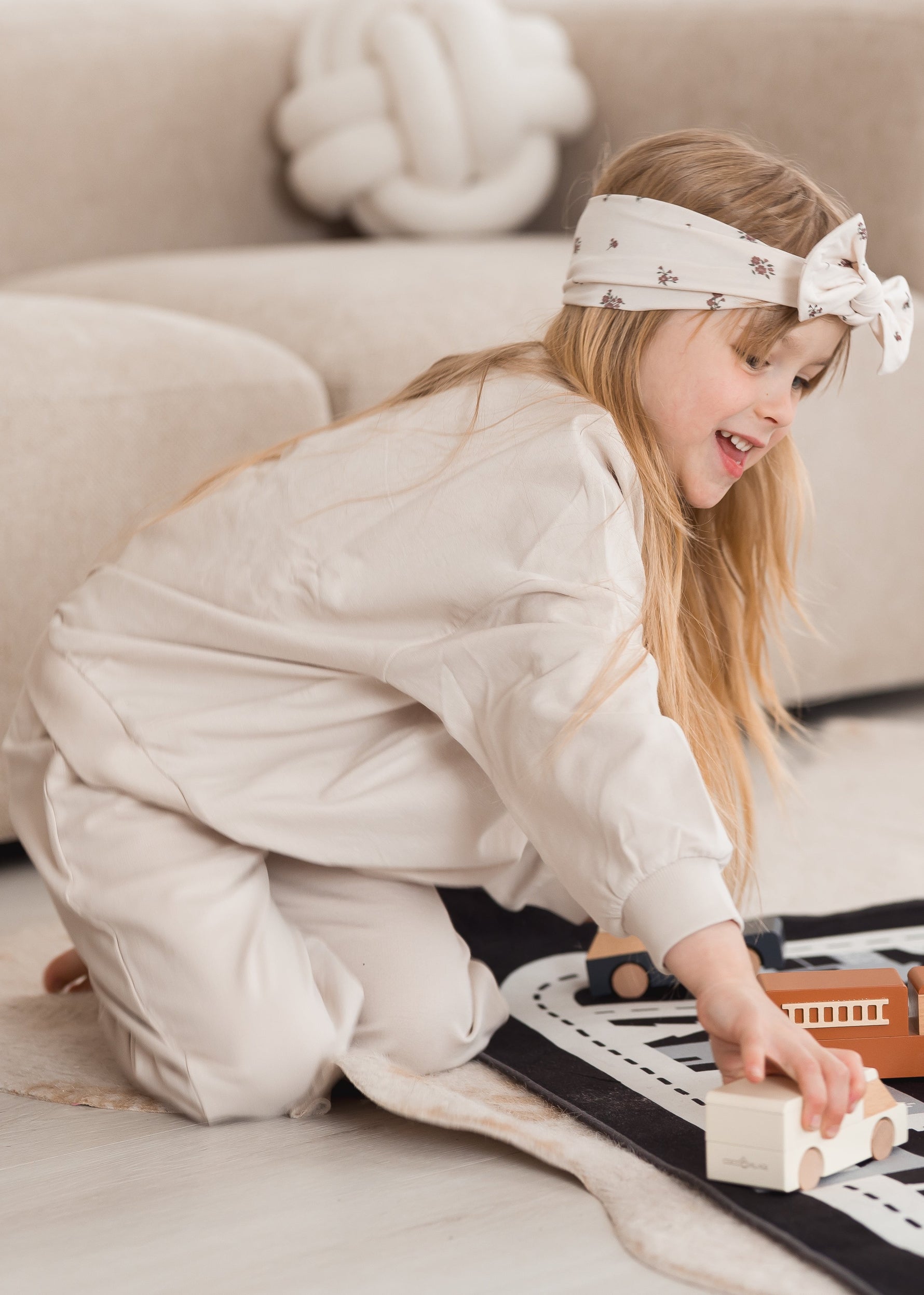 A girl wearing a GOTS certified organic cotton jogger set by Milana Label while she plays on the floor.