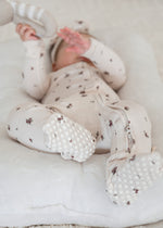 A close up of a Milana Label sleeper in the colour Birch Floral highlighting the foot grips on the feet. 
