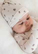 Baby girl in her Milana Label knot hat and matching sleeper on a neutral background