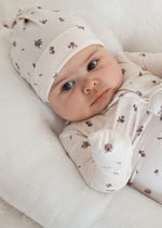 Baby girl in her Milana Label knot hat and matching sleeper on a neutral background
