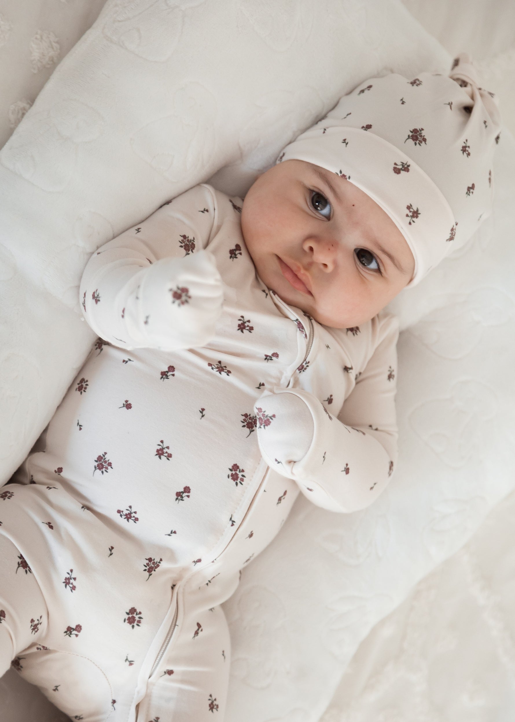 Baby in a sleeper with matching knot hat in the colour Birch Floral by Milana Label.