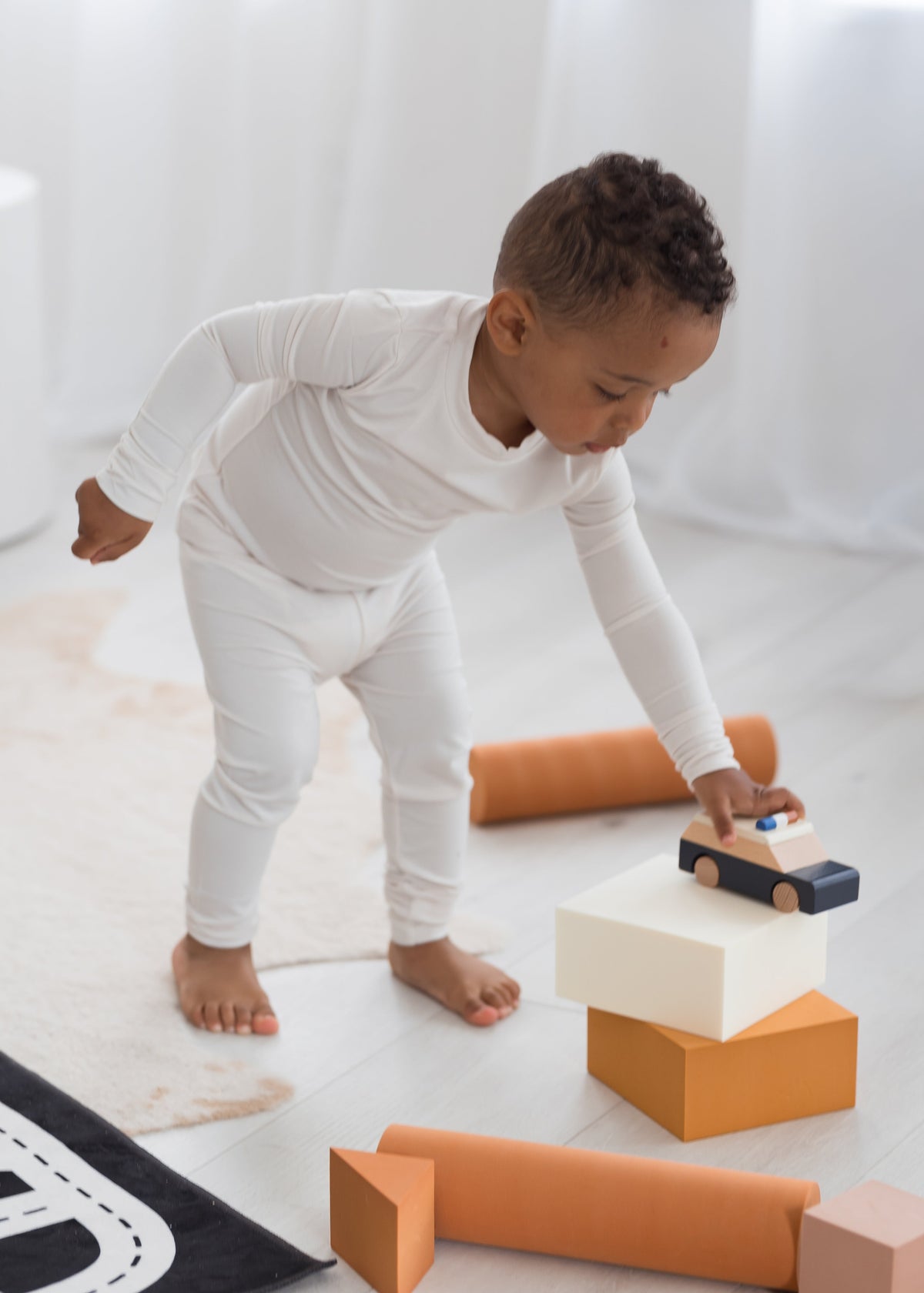 Toddler playing with cars on the floor in his Milana Label two piece PJ set in the colour Birch.