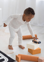 Toddler playing with cars on the floor in his Milana Label two piece PJ set in the colour Birch.