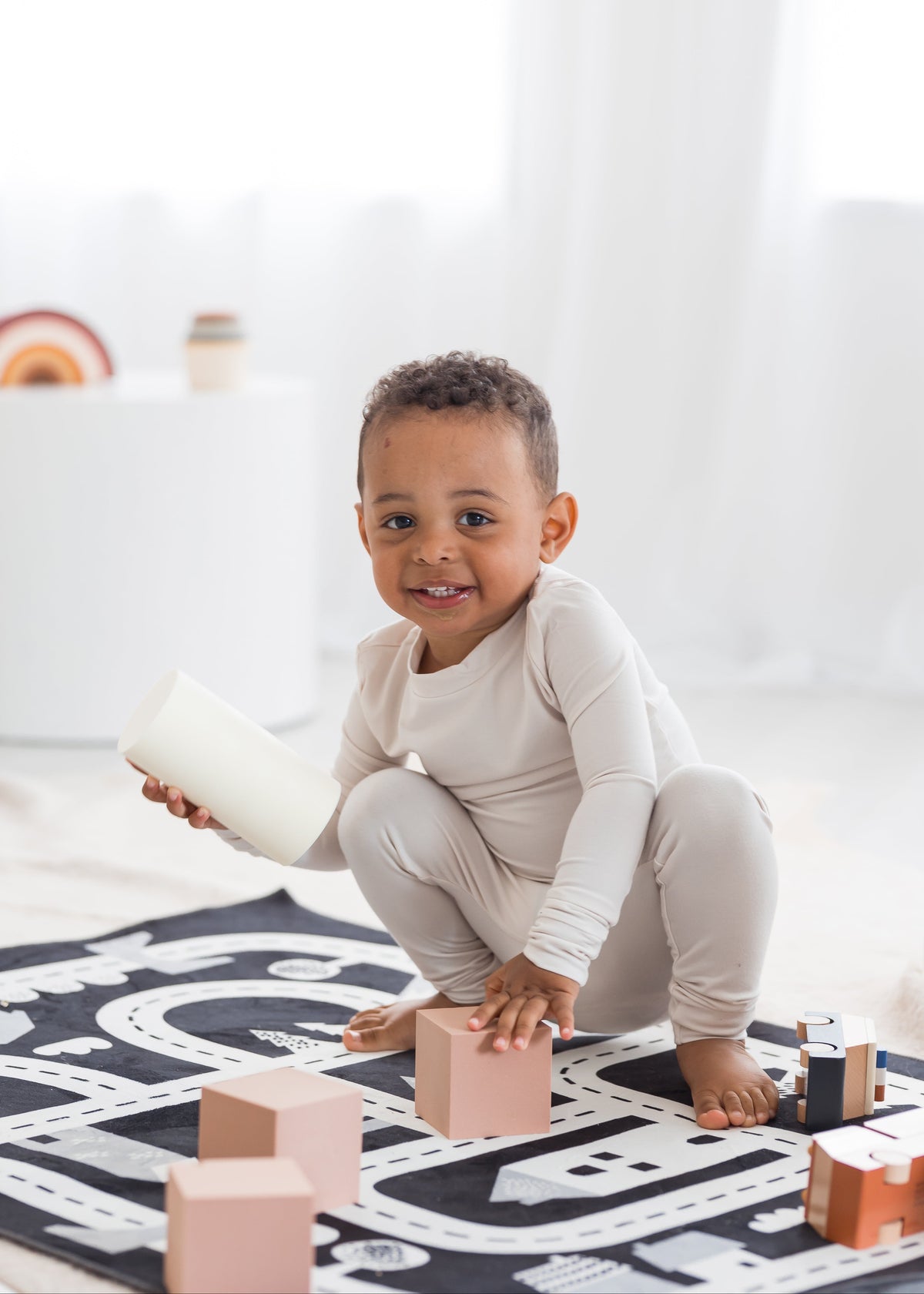 Toddler smiling and playing on the floor with blocks in his neutral Milana Label PJ set.