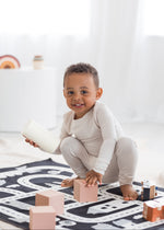 Toddler smiling and playing on the floor with blocks in his neutral Milana Label PJ set.