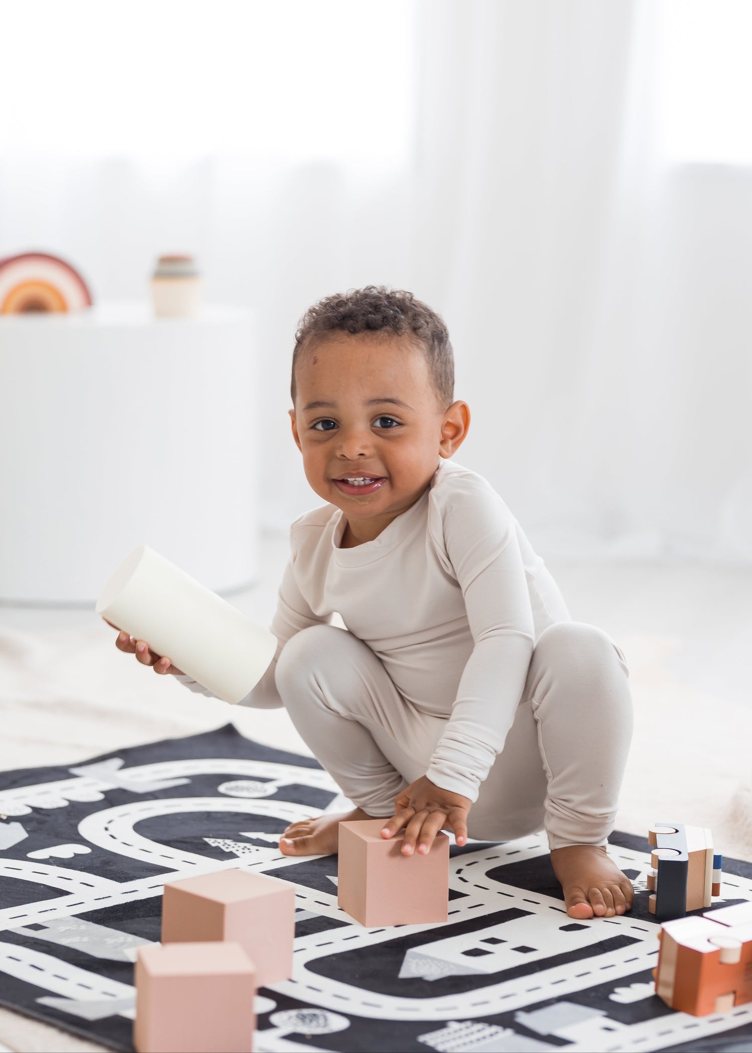 Toddler smiling and playing on the floor with blocks in his neutral Milana Label PJ set.