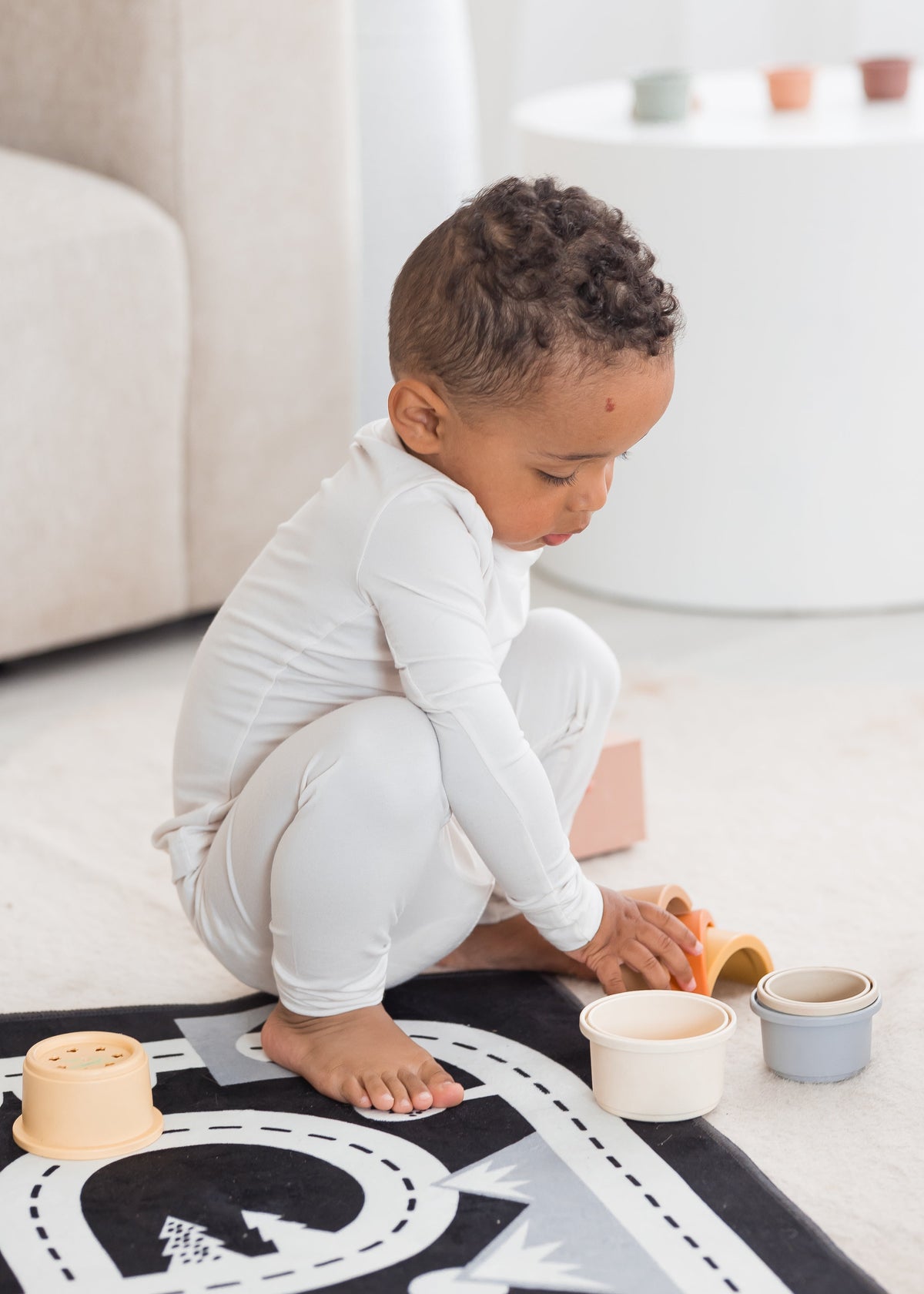 Toddler boy playing on the floor with blocks in his neutral PJ set by Milana Label.