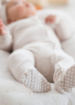 Infant wearing the premium solid Birch sleeper by Milana Label, showing the protective non-slip foot details.