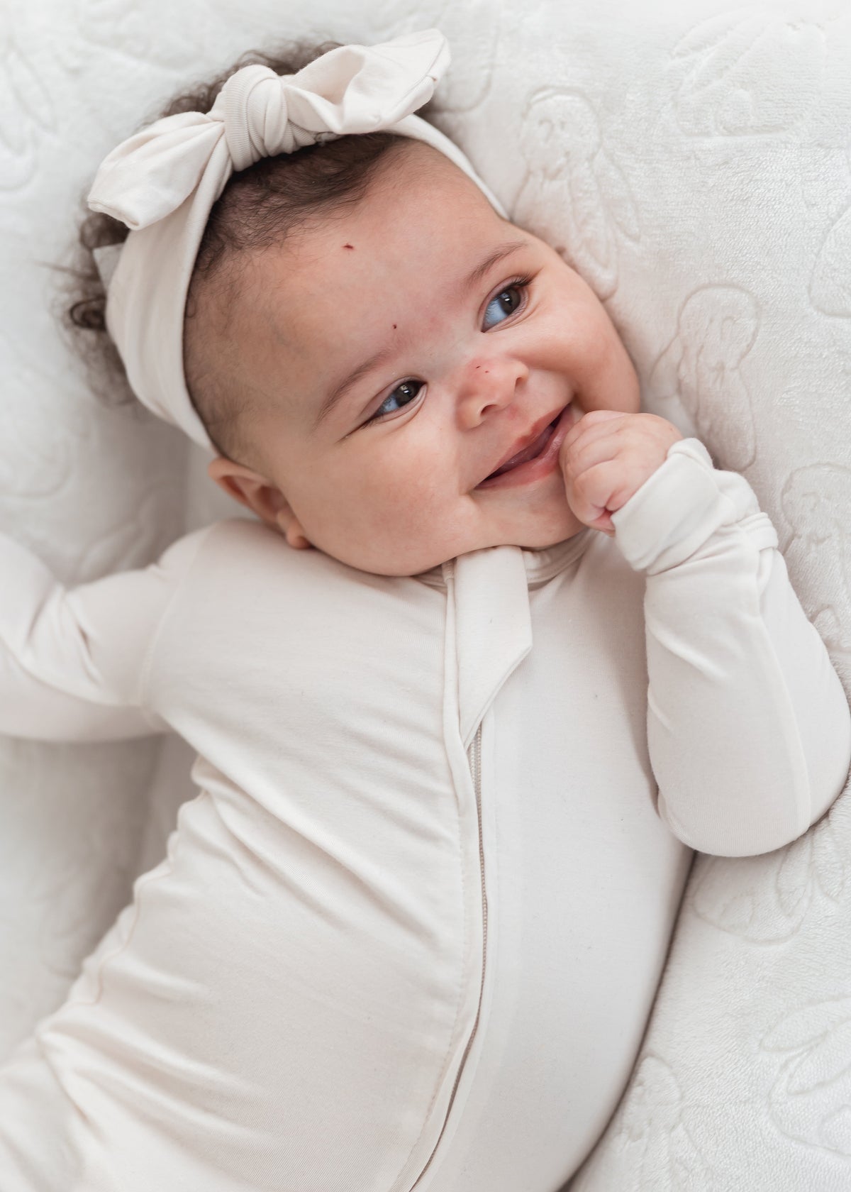 Baby girl in her Milana sleeper in the colour Birch.