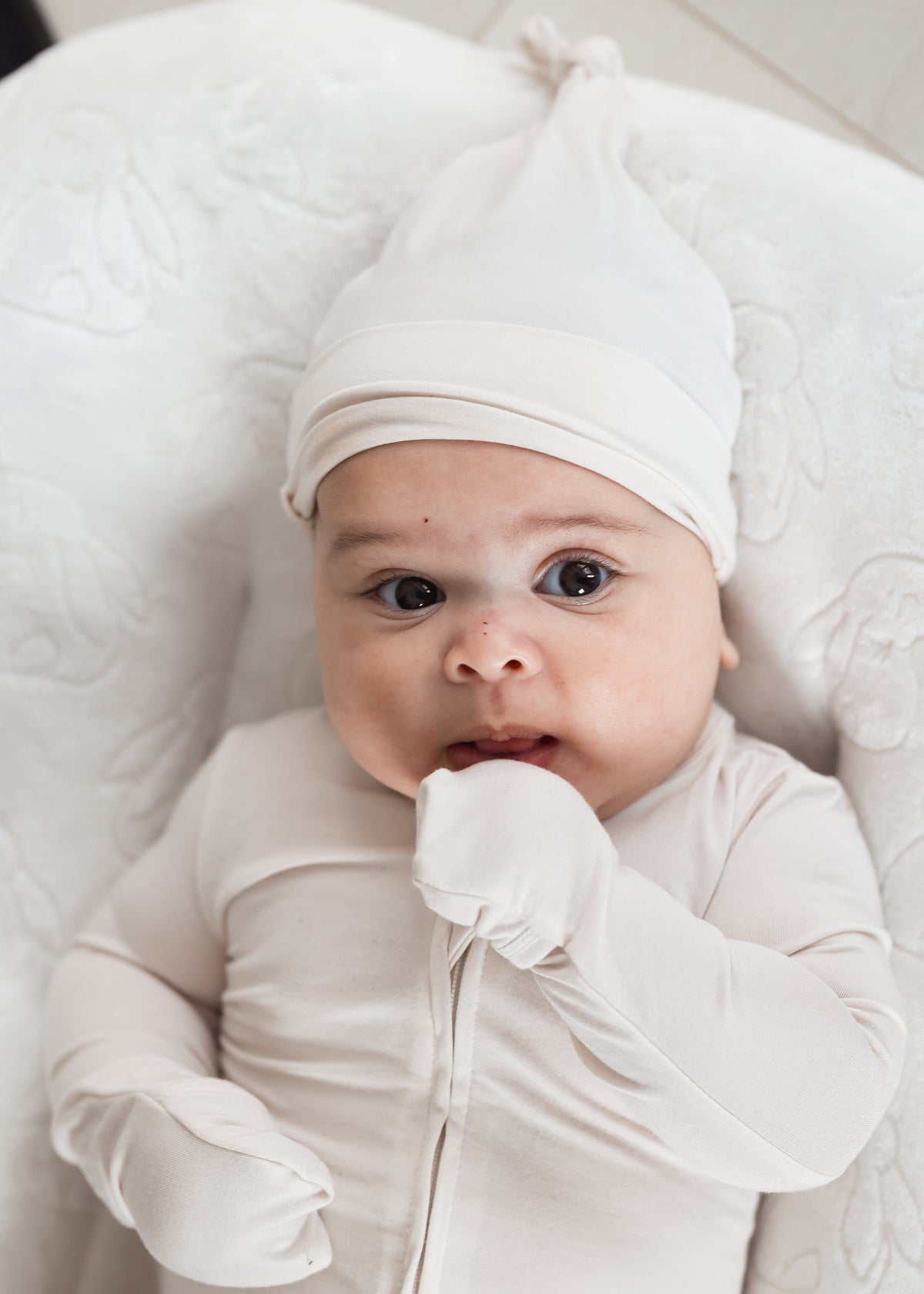 Baby wearing a Milana Label sleeper with matching knot hat while laying in a neutral lounger.