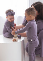 Siblings wearing matching Milana Soft TENCEL PJ's in the colour Wild Mulberry playing with a stacking toy.