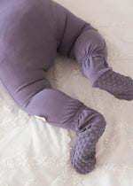 Detailed close-up of a baby's legs and feet wearing a Wild Mulberry purple sleeper, highlighting the patterned grip soles on the footies and elastic ankle backing.