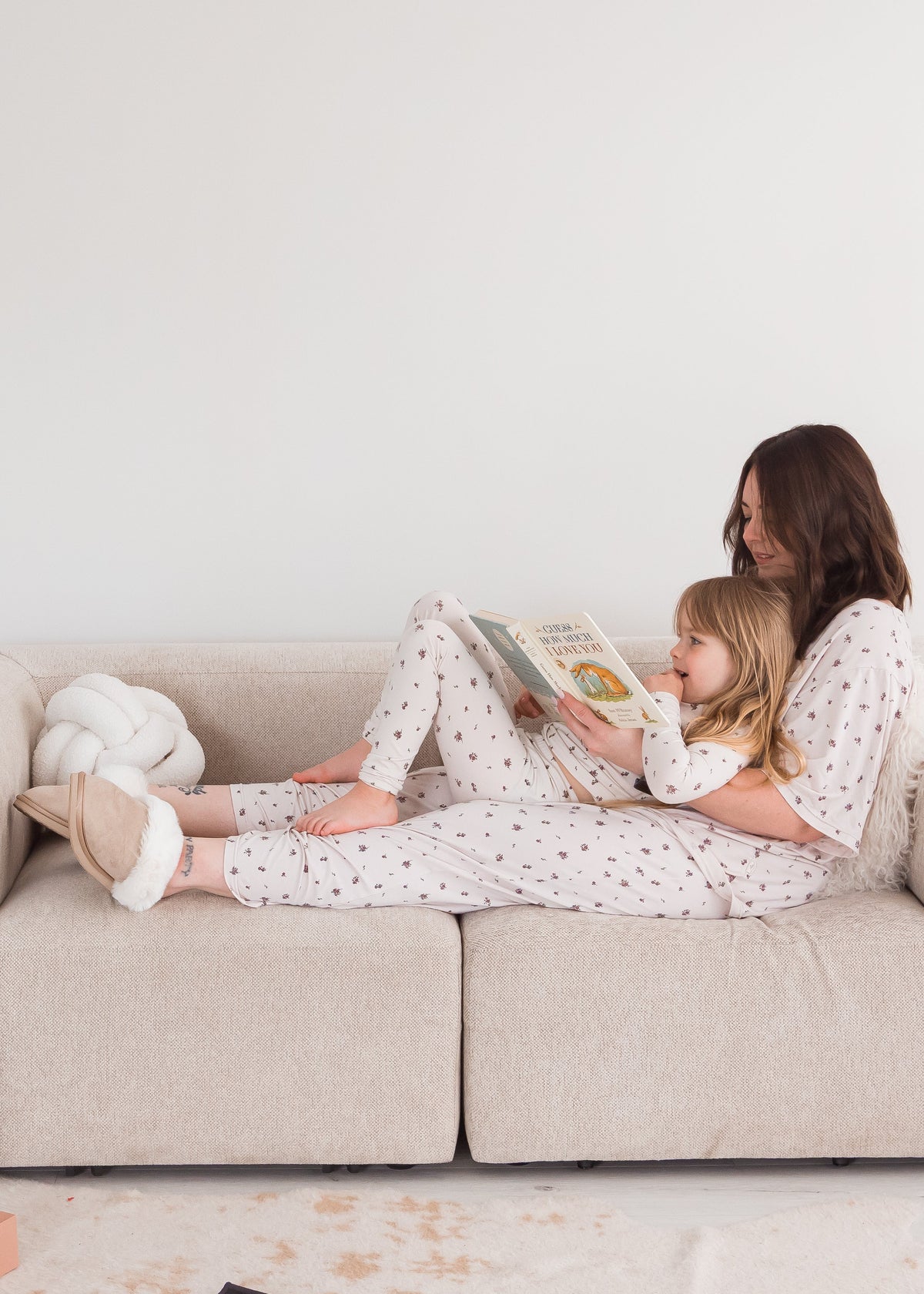A mom and her daughter in their matching Milana PJ sets sitting on a neutral couch.