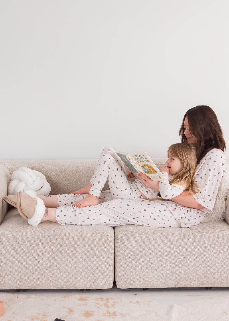 A mom and her daughter in their matching Milana PJ sets sitting on a neutral couch.
