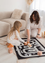 A mom and her daughter playing with cars on the floor in their matching Milana PJ sets.