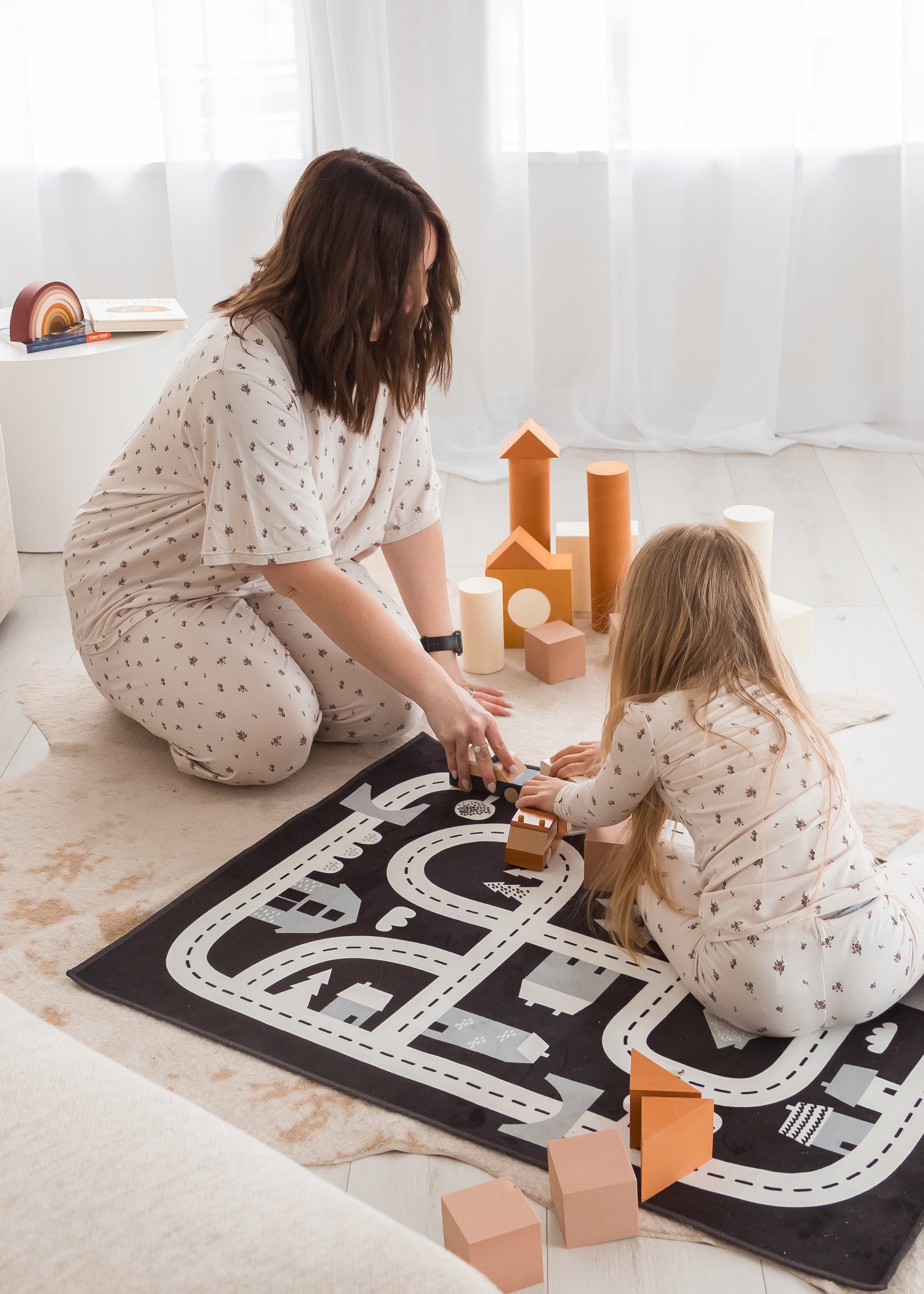 A mom and her daughter in matching Milana Label loungewear while playing with toys on the floor together.