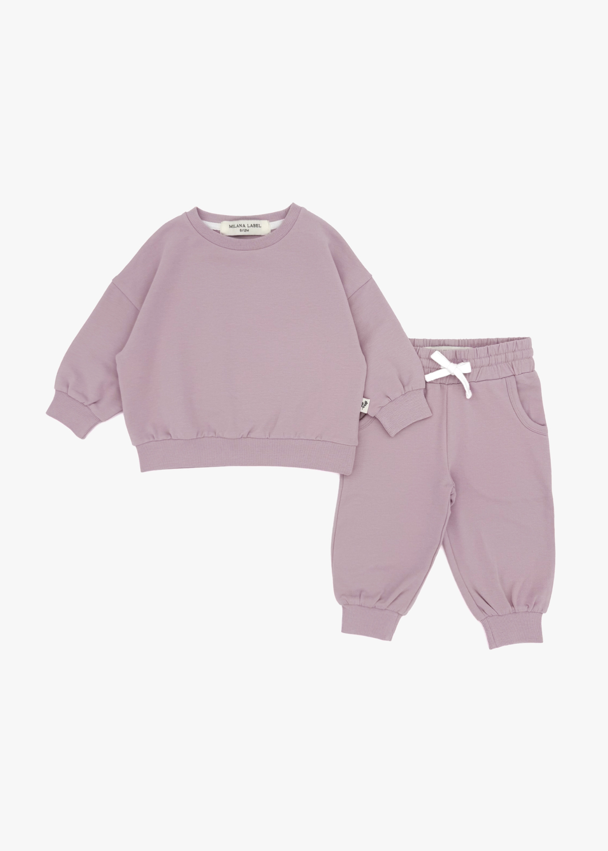 A flat lay product shot of a matching children's organic cotton jogger set in pale orchid, featuring a muted dusty pink oversized sweatshirt and matching jogger pants with a white drawstring bow against a white background.