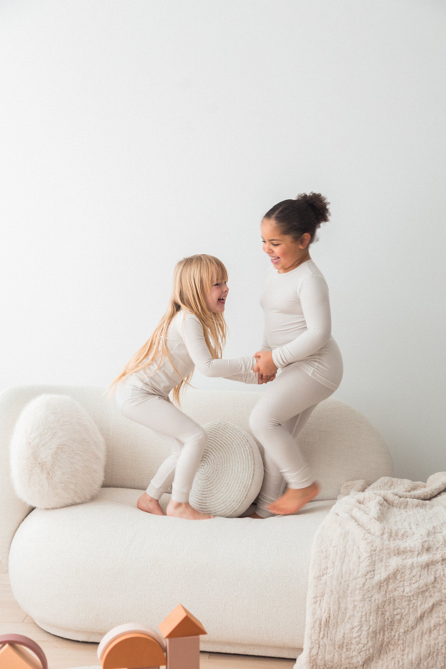 Two girls playing on the couch in their matching Milana Label pj sets.