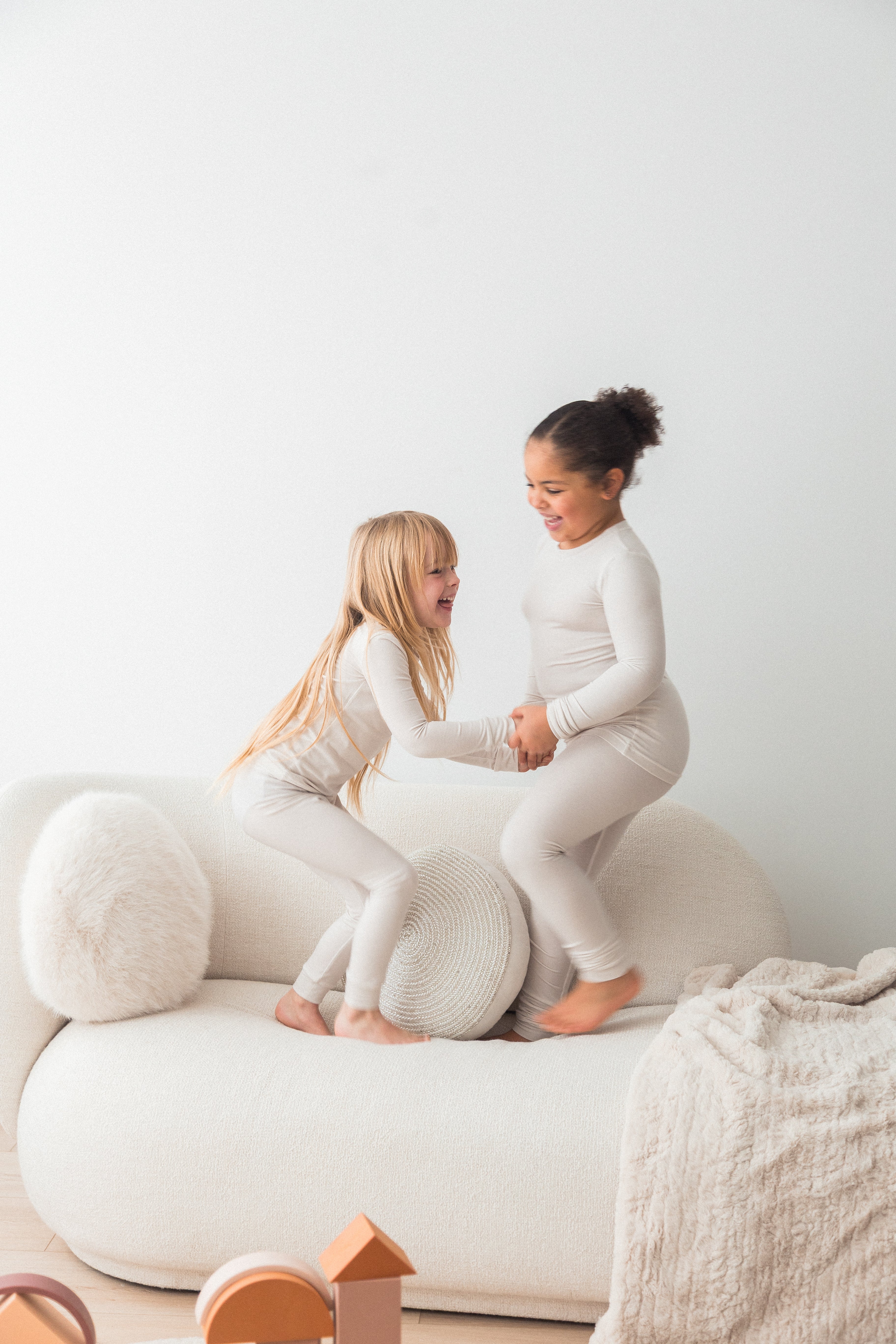Two girls playing on the couch in their matching Milana Label pj sets.
