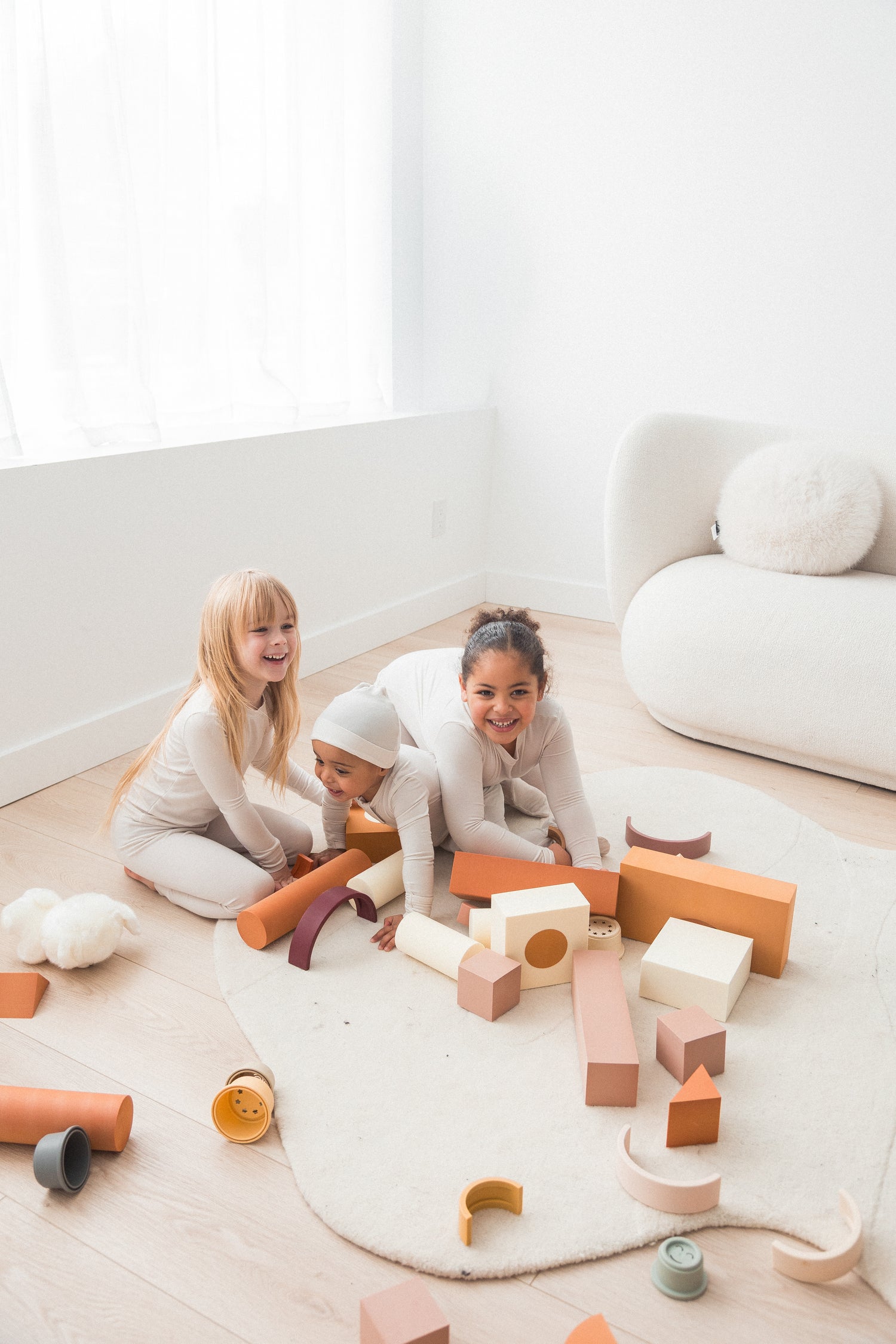 Three kids playing together on the floor in their matching Milana Label outfits.