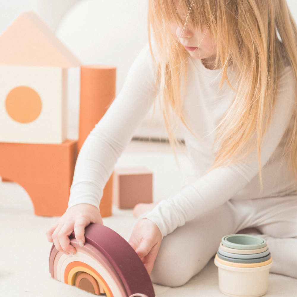 Girl playing on the floor with blocks in her neutral Milana Label pj set.