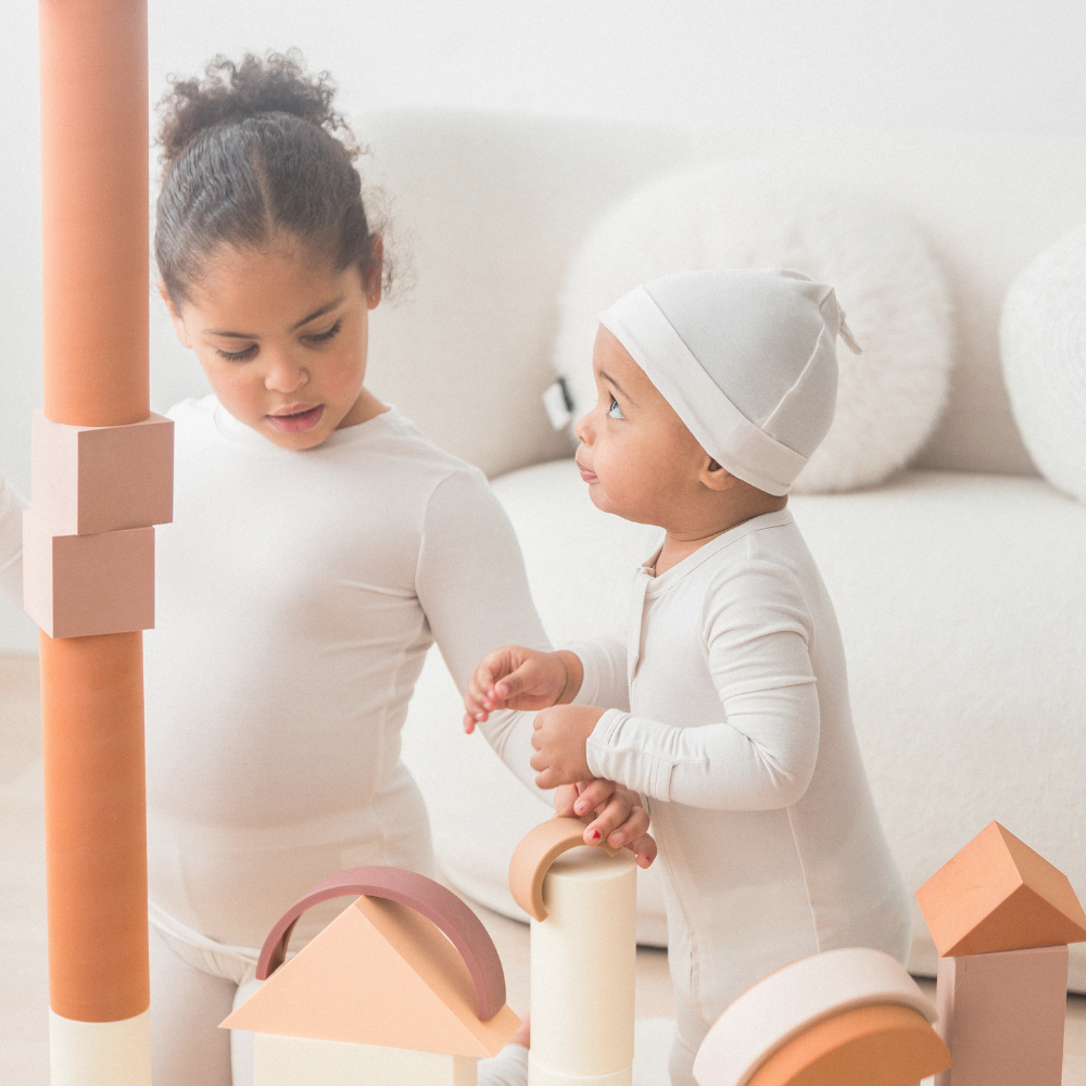 Two kids playing on the floor with blocks in their matching Milana Label pjs.
