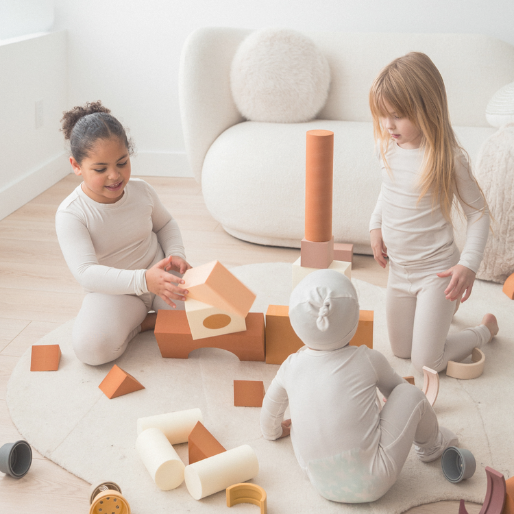 Three children playing with blocks in their matching Milana Label pj sets.