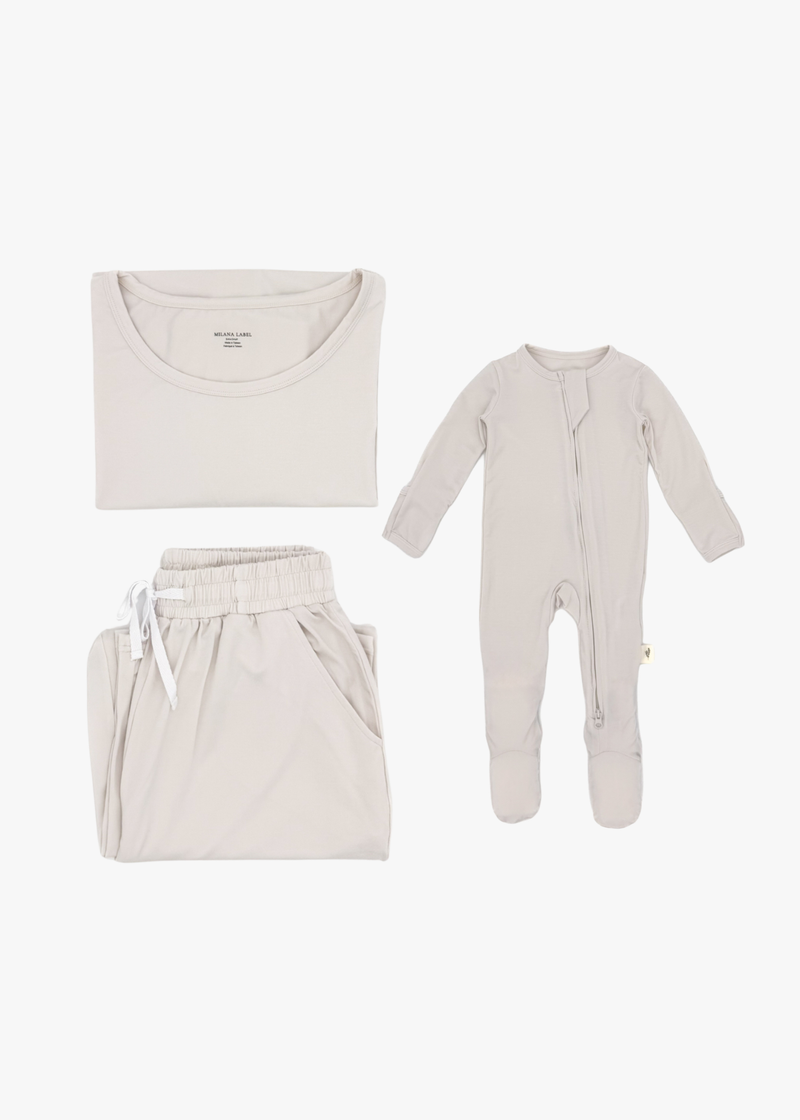 Milana Label mommy and me sleeper bundle in Birch, adult two-piece lounge set and baby zip footie sleeper laid flat together.