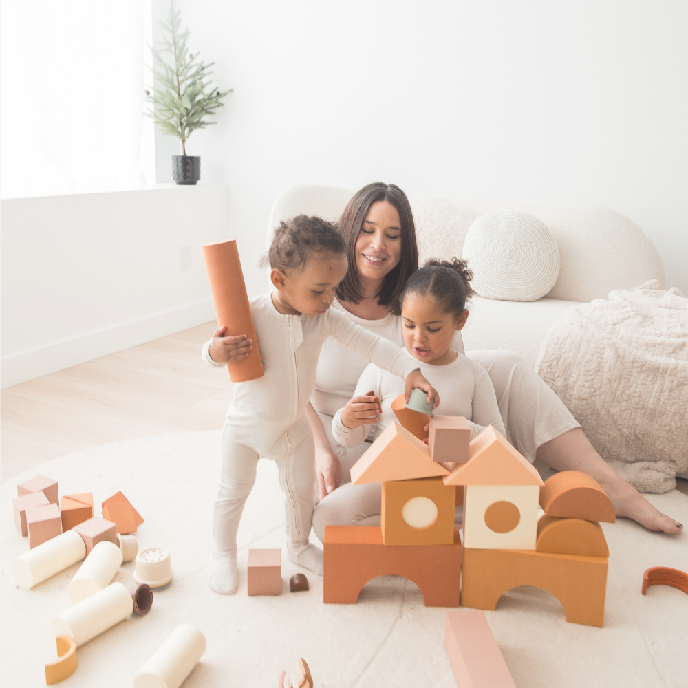 A mom and her two kids playing with blocks in their matching Milana Label pjs.