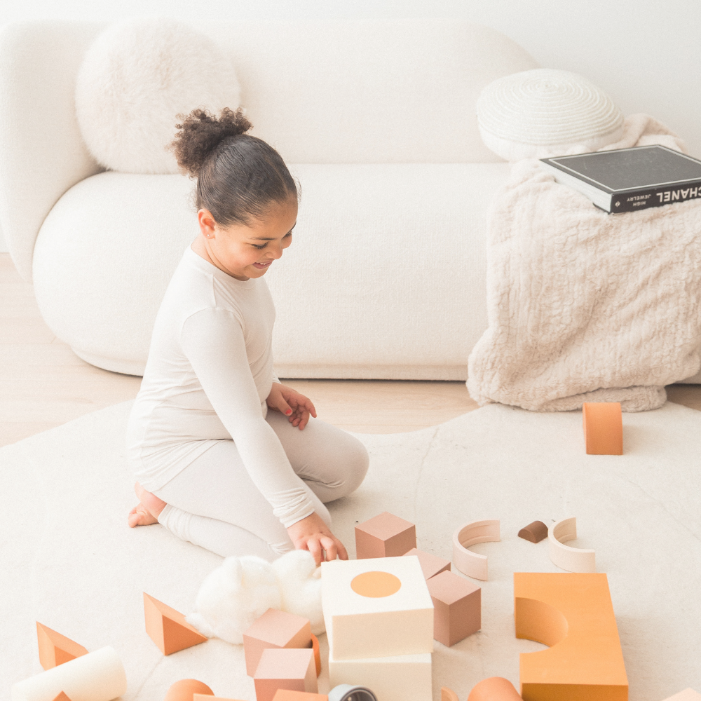 Child playing with blocks in her neutral Milana Label outfit.