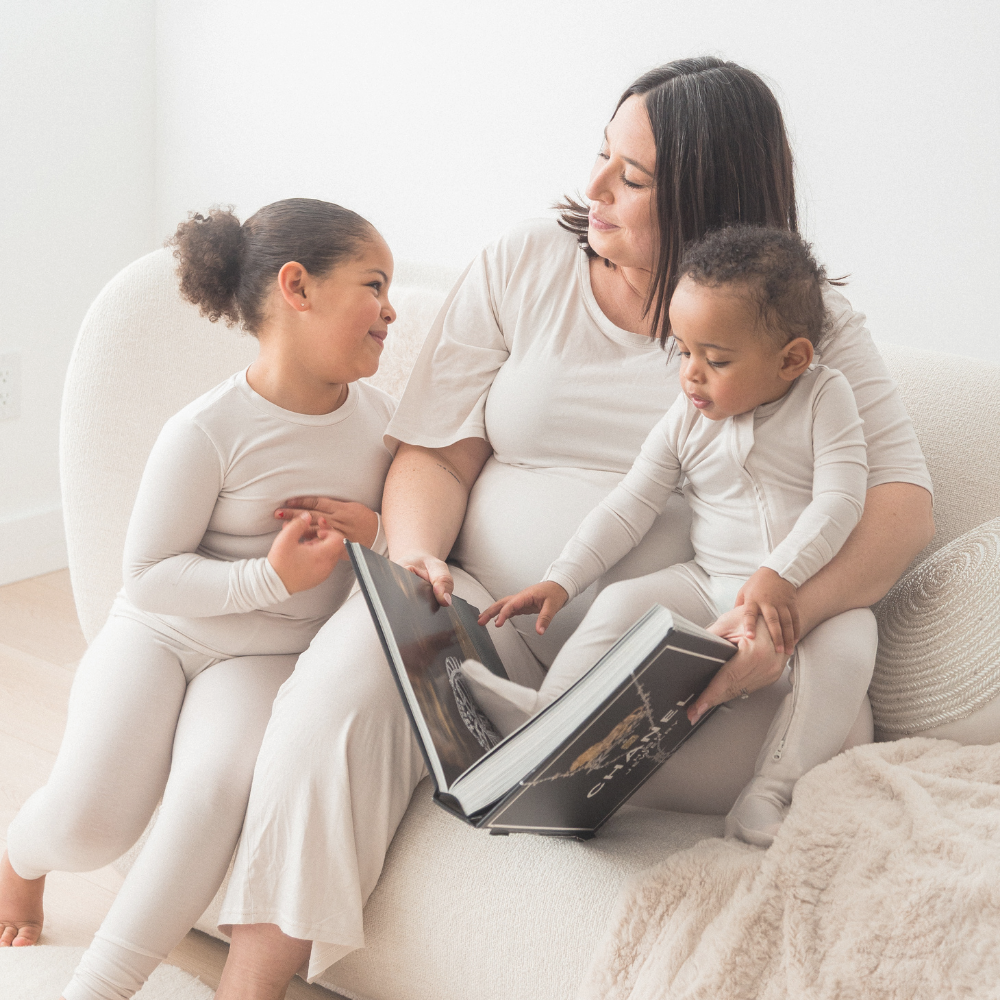 A mom reading to her two kids while wearing matching Milana Label pjs.