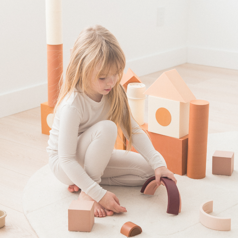 Girl playing with blocks on the floor in her neutral Milana Label pjs.