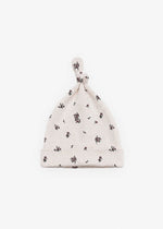 Milana Label knotted baby hat in Birch Floral, a warm cream fabric with a scattered dark floral print, photographed flat against a white background.