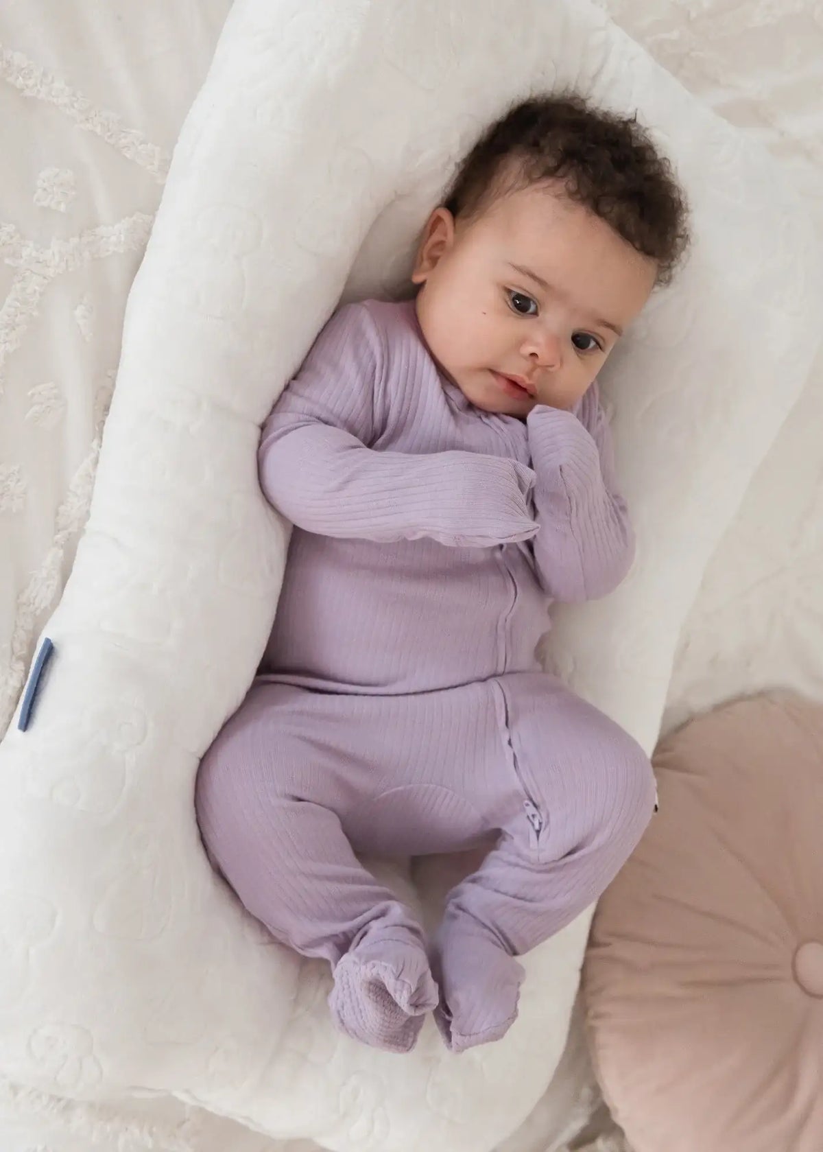 A baby wearing the fold-over mitts feature on the Milana organic sleeper.