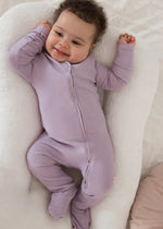 A smiling baby wearing a Lavender Blush organic cotton footie PJ.