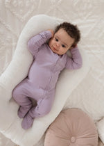 A baby wearing organic cotton long sleeve footie PJs by Milana Label.