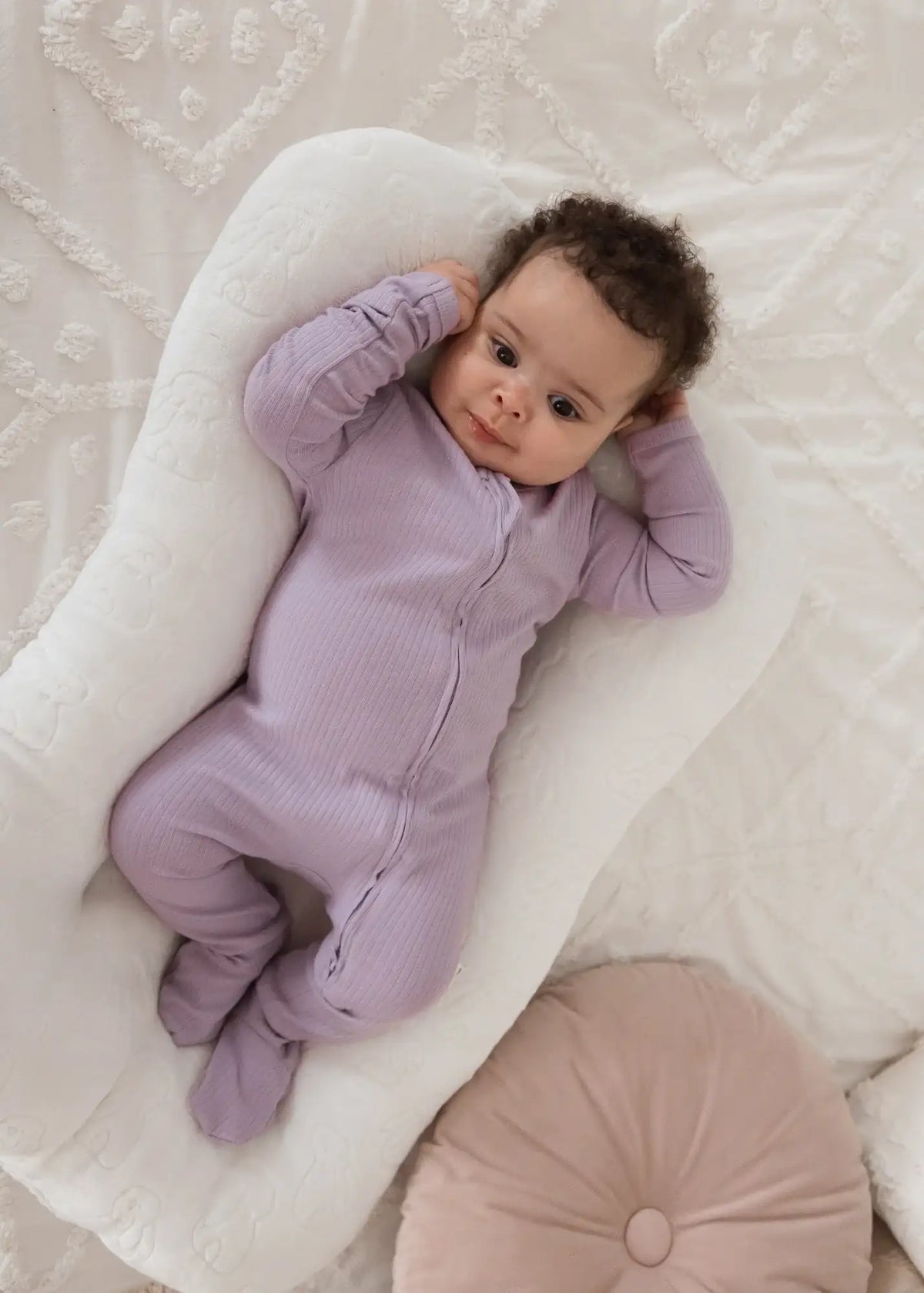 A baby wearing organic cotton long sleeve footie PJs by Milana Label.