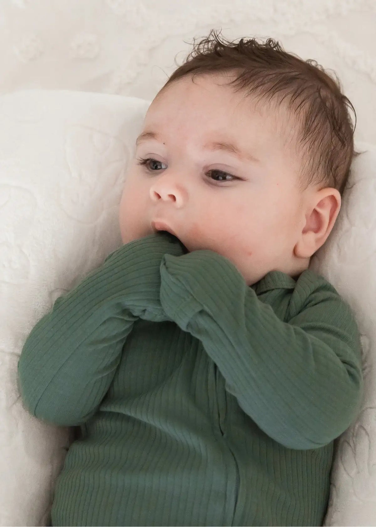 A close-up of the fold-over mitt feature on an organic cotton footie in the colour Pine.