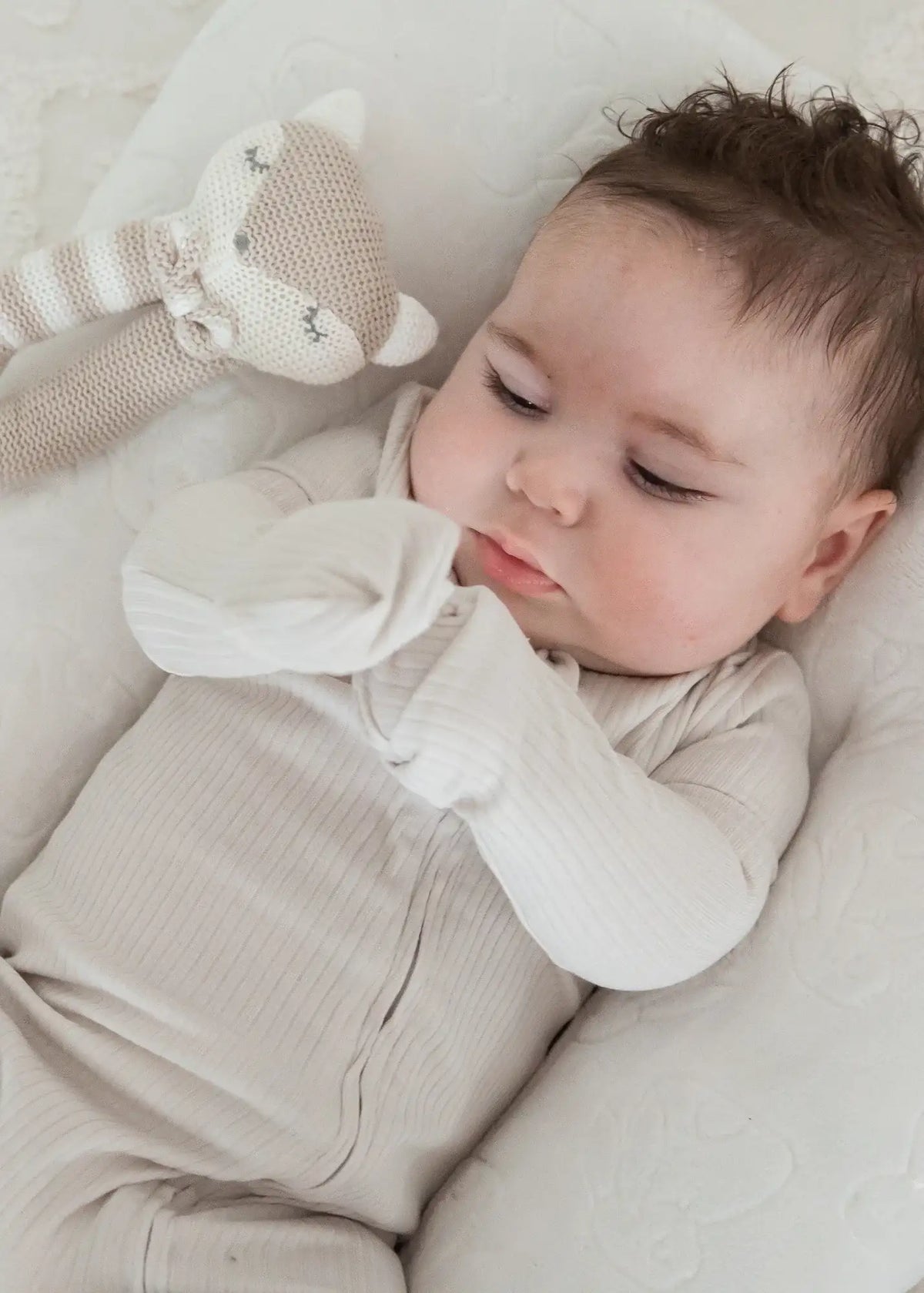 A baby wearing the fold-over mitt feature on a Milana Label footie.